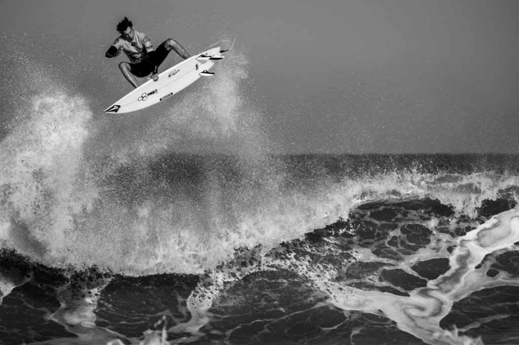 black and white surfer launching off a wave